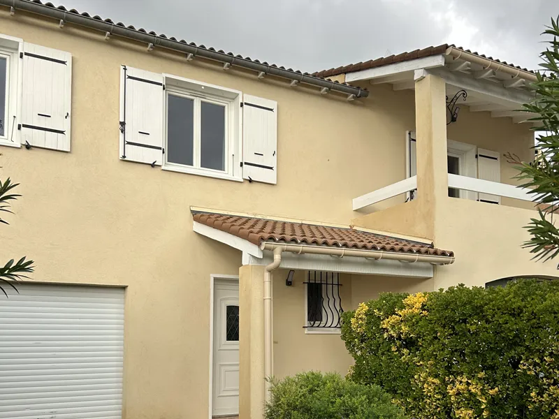 Façade terminée en enduit ton pierre avec volets blancs