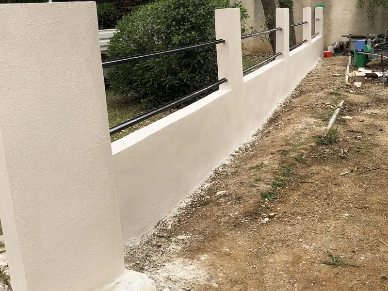 Mur de clôture enduit blanc avec lisses métalliques noires