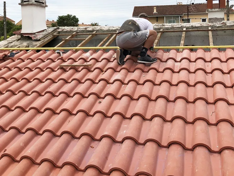 Artisan travaillant sur la rénovation d'une toiture en tuiles